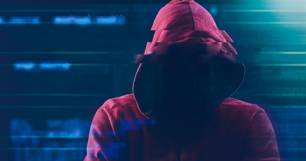 Person im Kapuzenpullover mit verdecktem Gesicht vor verschwommenen Codezeilen